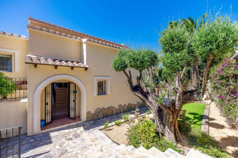 Garden exterior at an elegant Mediterranean villa in Altea Hills with arched entrance, mature olive tree and Mediterranean planting