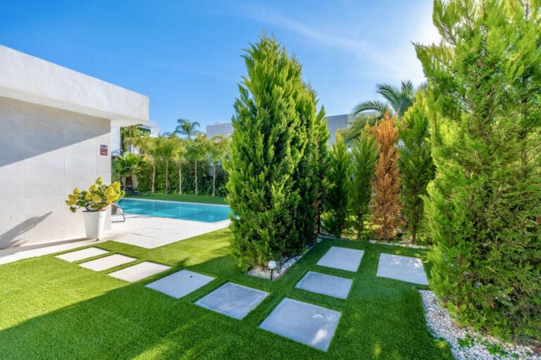 Garden lawn with stepping stone pathway and privacy hedging at a modern oasis villa near Arenal-Bol Beach in Calpe.