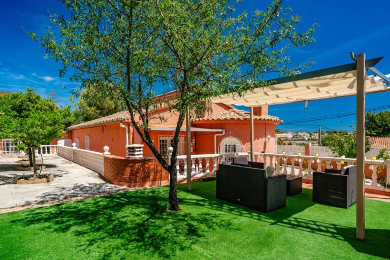 Garden lounge area with pergola, artificial grass and outdoor seating at a renovated Mediterranean villa in La Cometa, Calpe.