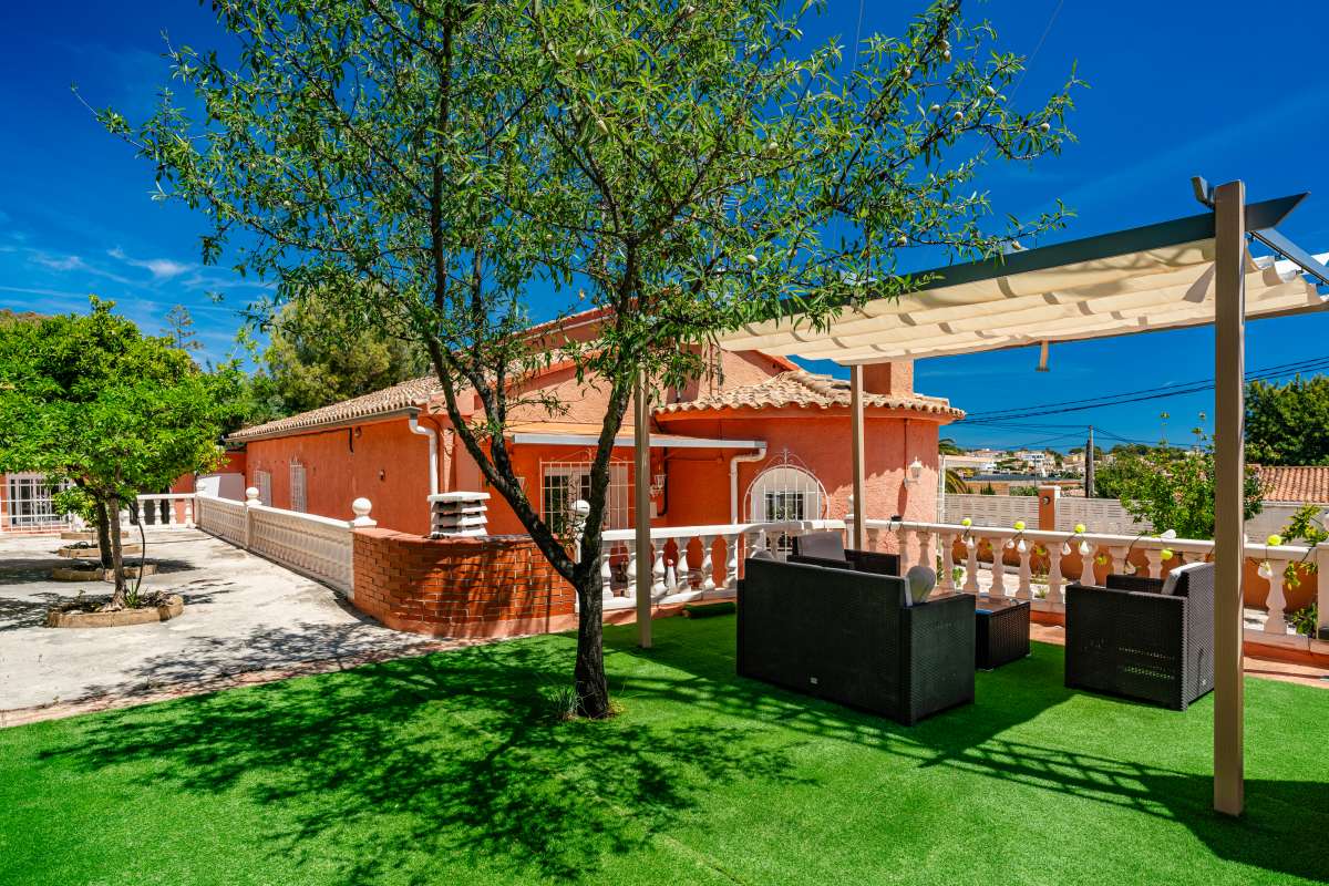 Garden lounge area with pergola, artificial grass and outdoor seating at a renovated Mediterranean villa in La Cometa, Calpe.