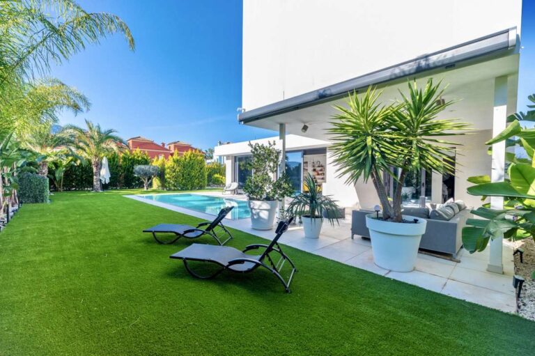 Garden lounge area with sun loungers, lawn and shaded terrace at a modern oasis villa in Calpe.