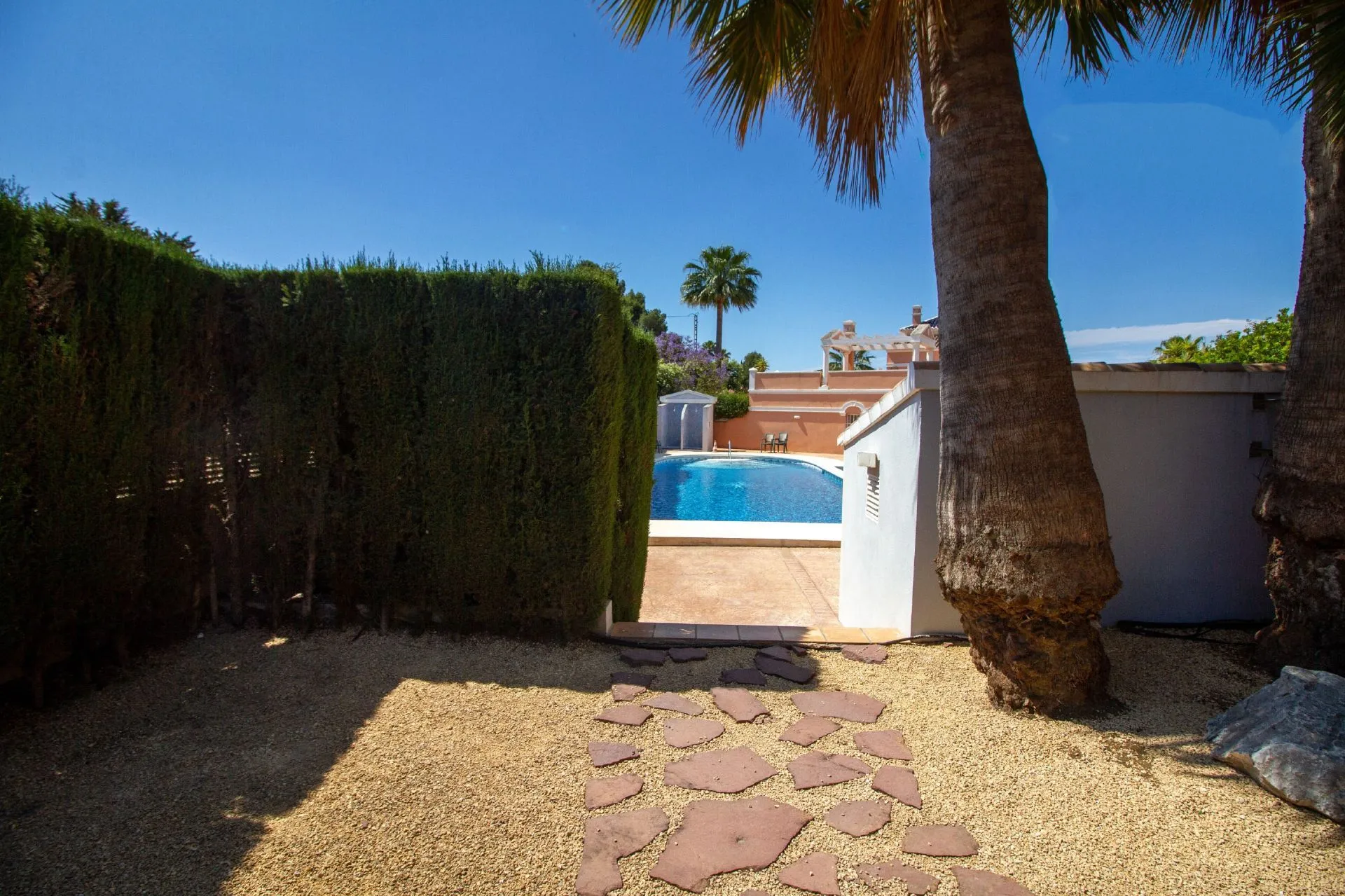 Garden path leading to communal pool near bungalow in La Vallesa Calpe