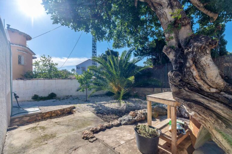 Garden seating area with mature tree and shaded outdoor space at a contemporary villa in Calpe.