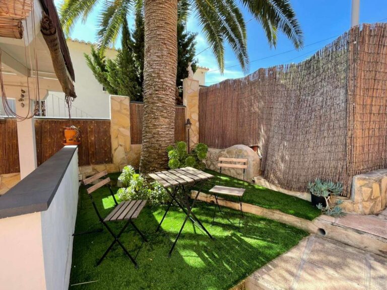 Garden seating area with palm tree and artificial grass at a refurbished villa with three independent apartments in Canuta, Calpe.