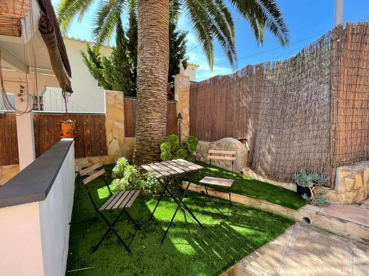 Garden seating area with palm tree and artificial grass at a refurbished villa with three independent apartments in Canuta, Calpe.