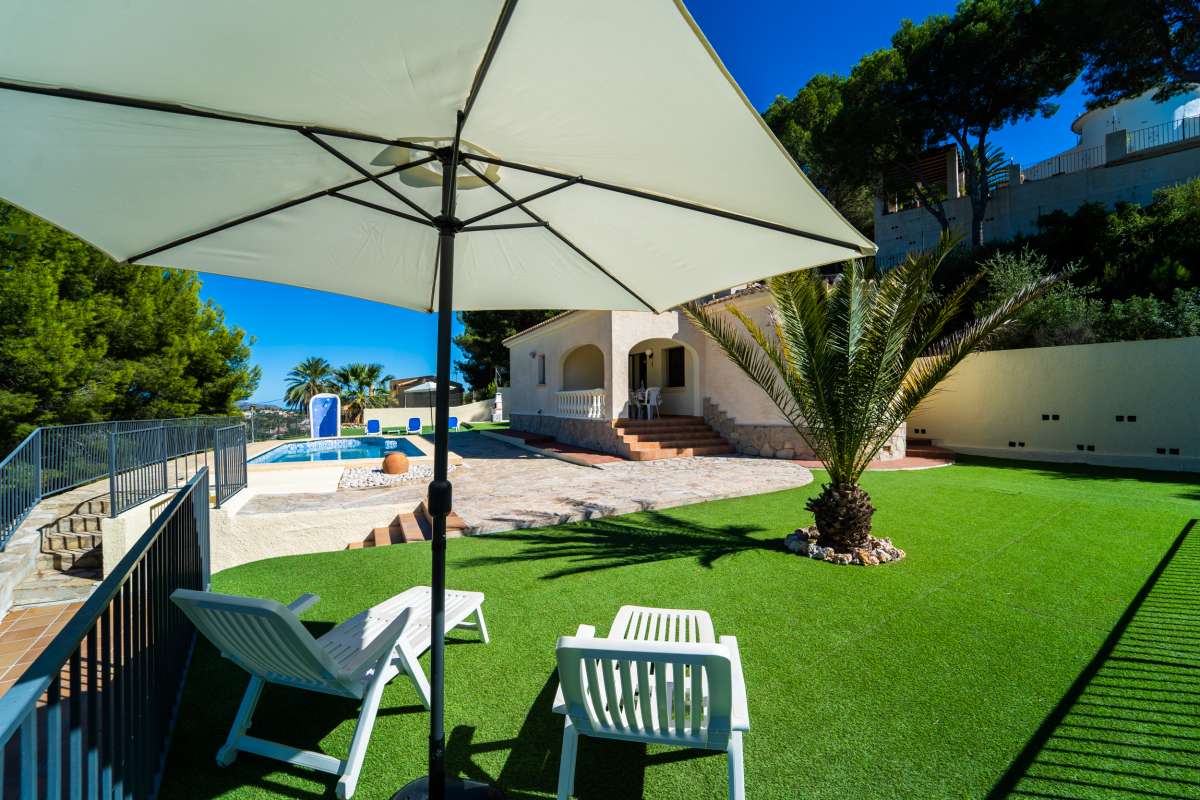 Garden seating area with sunshade, pool terrace and mountain surroundings at a Mediterranean villa in Calpe.