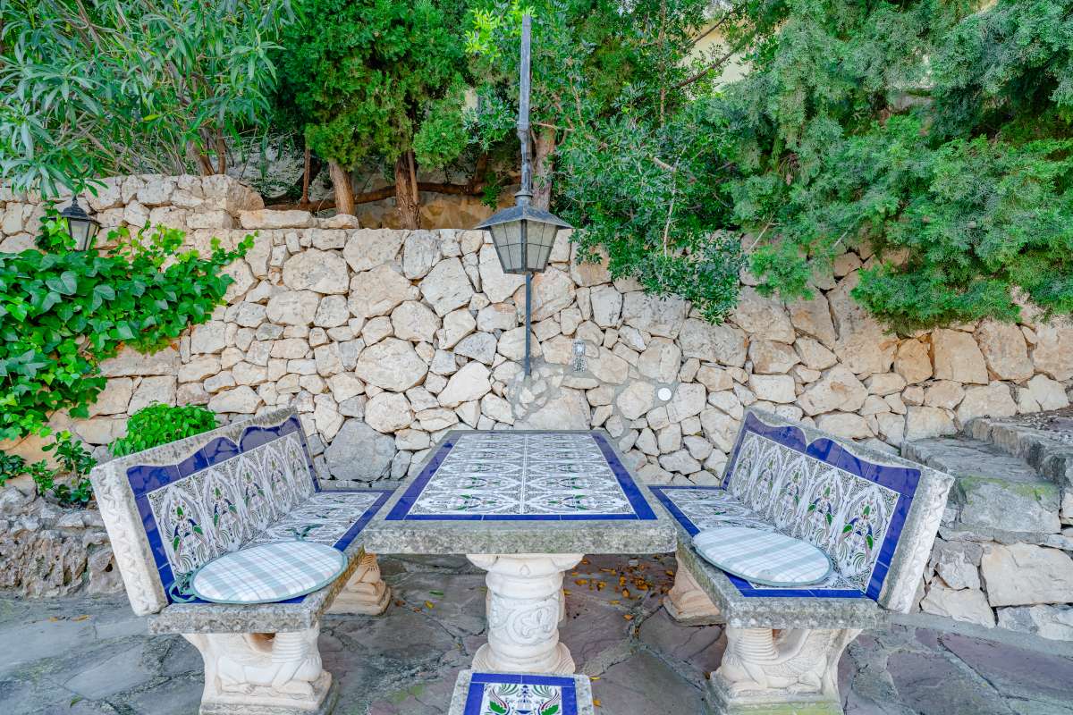 Garden seating area with tiled benches, stone wall and natural surroundings at a Mediterranean villa in Maryvilla, Calpe.