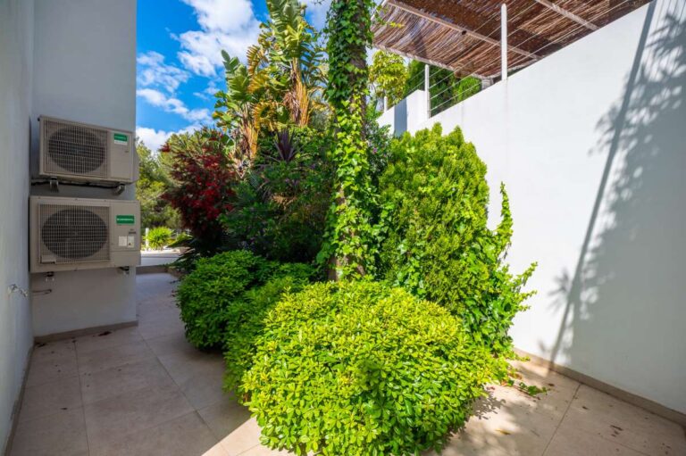 Garden side pathway at a modern villa in Altea Hills with Mediterranean planting, white exterior walls, air conditioning units and private outdoor space