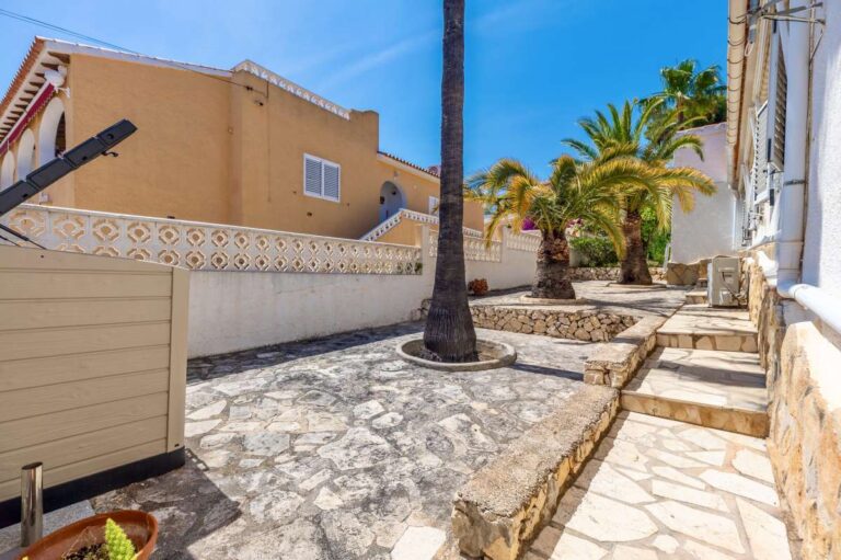 Garden steps at a renovated single-level villa in Moraira with stone paving, palm trees, side access and Mediterranean outdoor space