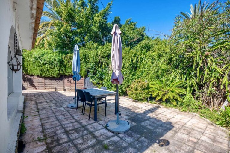 Garden terrace at a Mediterranean villa in Benissa Costa with outdoor dining area, parasols and mature Mediterranean planting