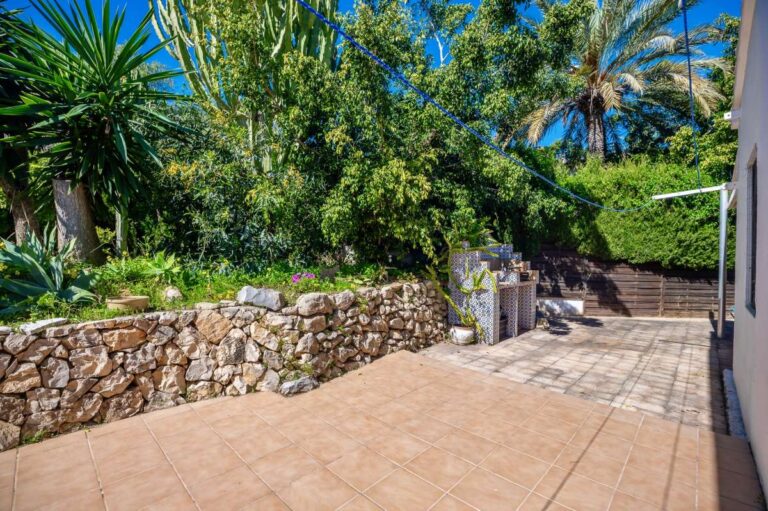 Garden terrace at a Mediterranean villa in Benissa Costa with stone walling, mature planting, palm trees and outdoor space