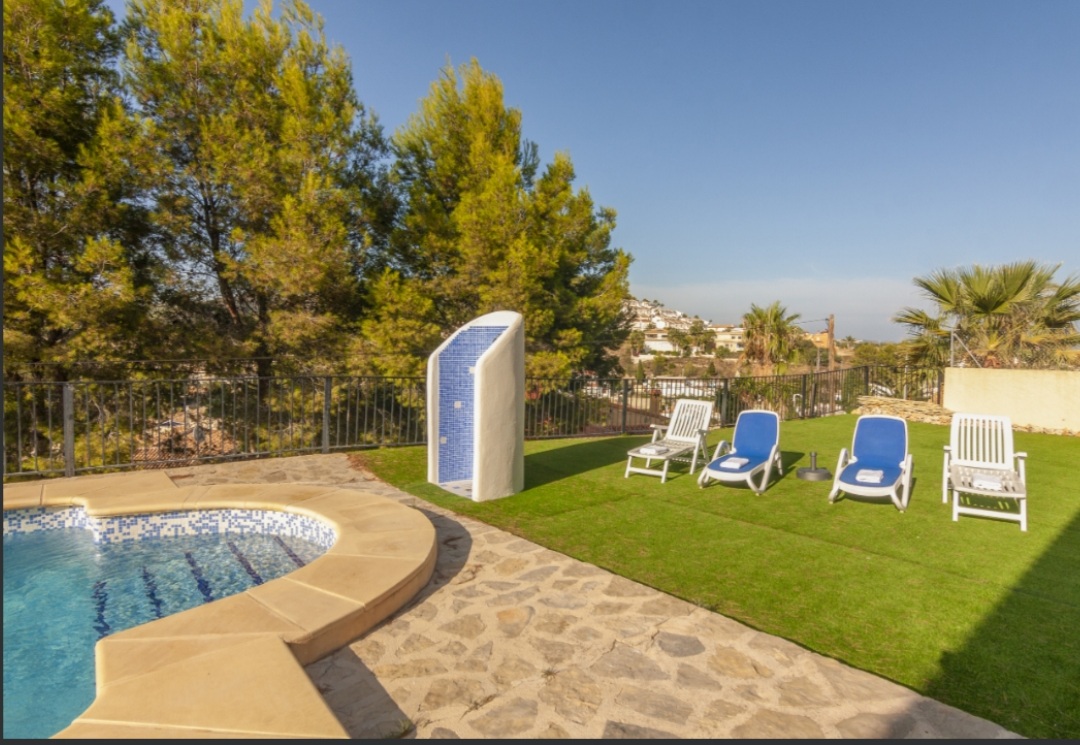 Garden terrace with private swimming pool, sun loungers and mountain surroundings at a Mediterranean villa in Calpe.