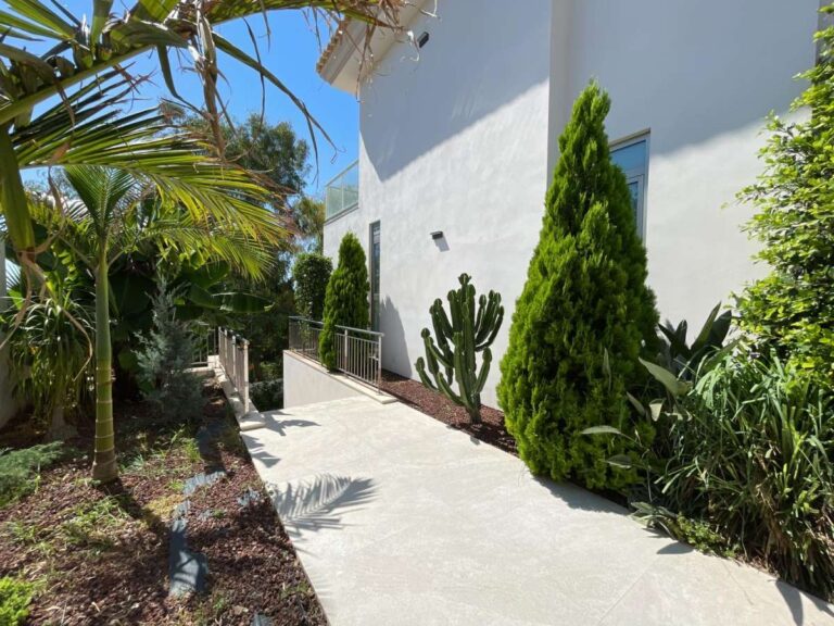 Garden walkway at a modern luxury villa in La Calalga, Calpe with Mediterranean planting, palm trees and side exterior access
