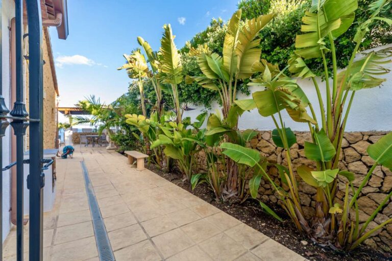 Garden walkway at a premium coastal villa on the Benissa Costa with tropical planting, stone walling and side exterior access