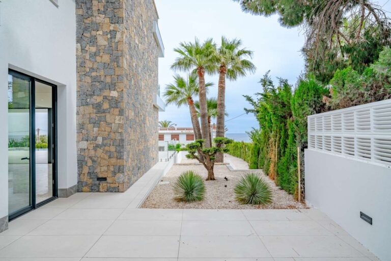 Garden walkway beside a modern villa in La Calalga, Calpe with palm trees, stone wall detail and landscaped outdoor space