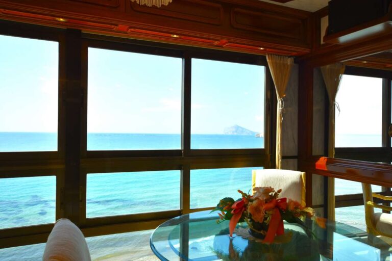 Glazed terrace with dining area and sea views inside a frontline double penthouse on Arenal Beach in Calpe.