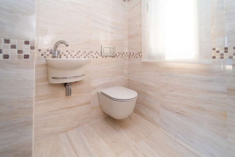 Guest bathroom inside a luxury villa in Calpe with wall-mounted basin, toilet, window and light tiled finish