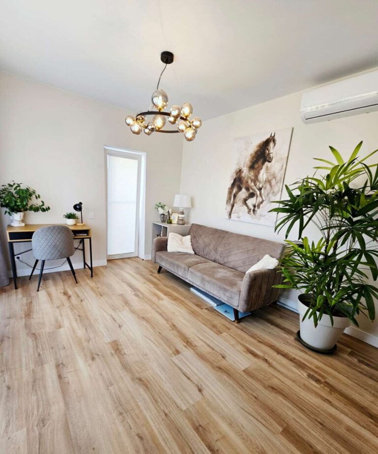 Guest bedroom inside a modern villa near Les Bassetes in Calpe with sofa bed, desk area, wood flooring and natural light