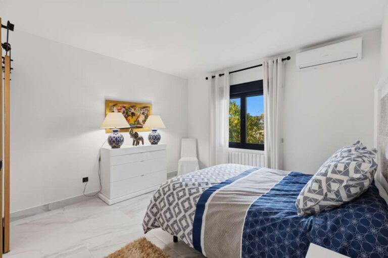 Guest bedroom inside a premium coastal villa on the Benissa Costa with blue bedding, bright white interior and air conditioning