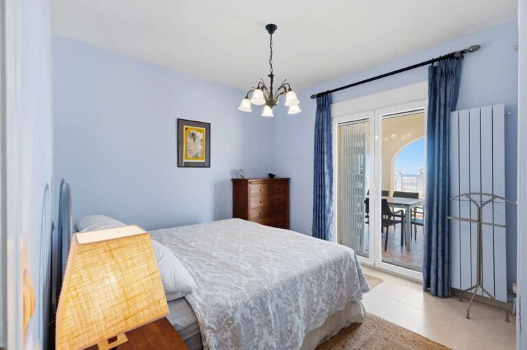 Guest bedroom inside an elegant Mediterranean villa in Altea Hills with terrace access, blue interior details and natural light