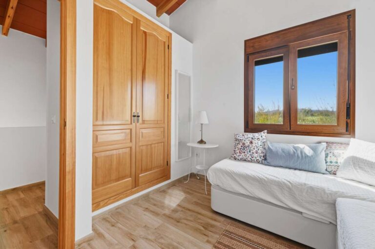 Guest house bedroom at a traditional Spanish finca near Moraira with wooden wardrobe, window, sofa bed and bright Mediterranean interior