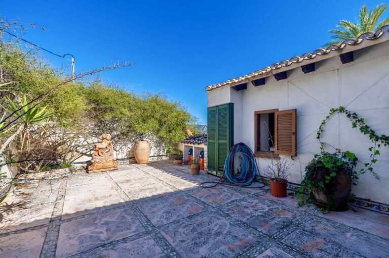 Guest house courtyard at a traditional Spanish finca near Moraira with tiled terrace, white exterior walls, wooden shutters and Mediterranean planting