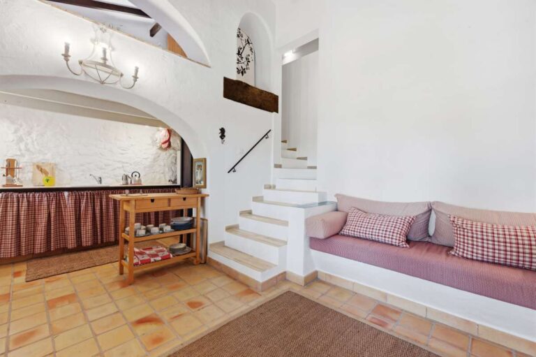 Guest house living area at a traditional Spanish finca near Moraira with staircase, built-in seating, kitchenette area and rustic Mediterranean style