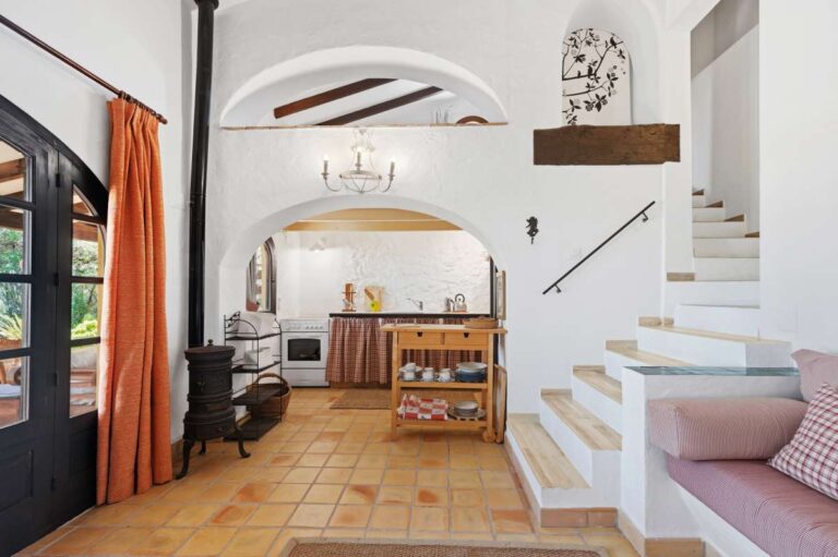 Guest house lounge inside a traditional Spanish finca near Moraira with kitchenette, staircase, built-in seating, tiled floor and rustic interior details