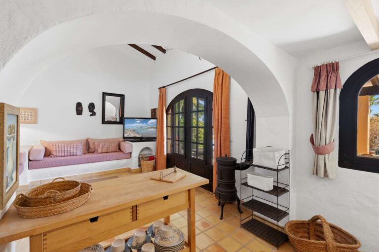Guest house sitting area at a traditional Spanish finca near Moraira with arched doorway, built-in seating, wood burner and rustic Mediterranean character