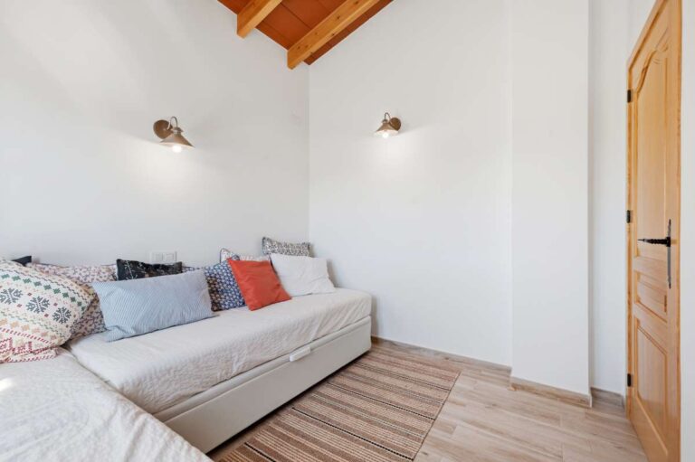 Guest house sofa bedroom at a traditional Spanish finca near Moraira with wooden ceiling, wall lighting, sofa bed and bright rustic interior