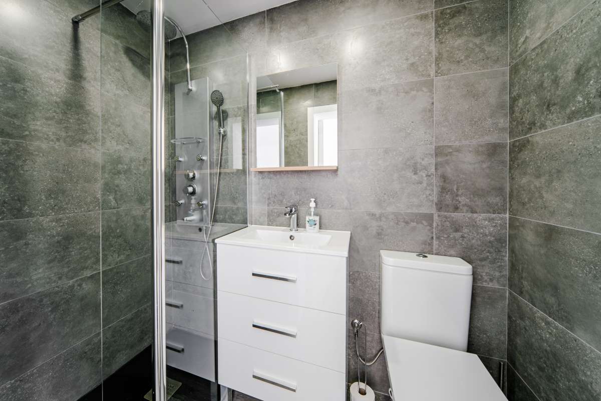 Guest suite bathroom with shower, vanity and grey tile finish at a renovated Mediterranean villa in La Cometa, Calpe.