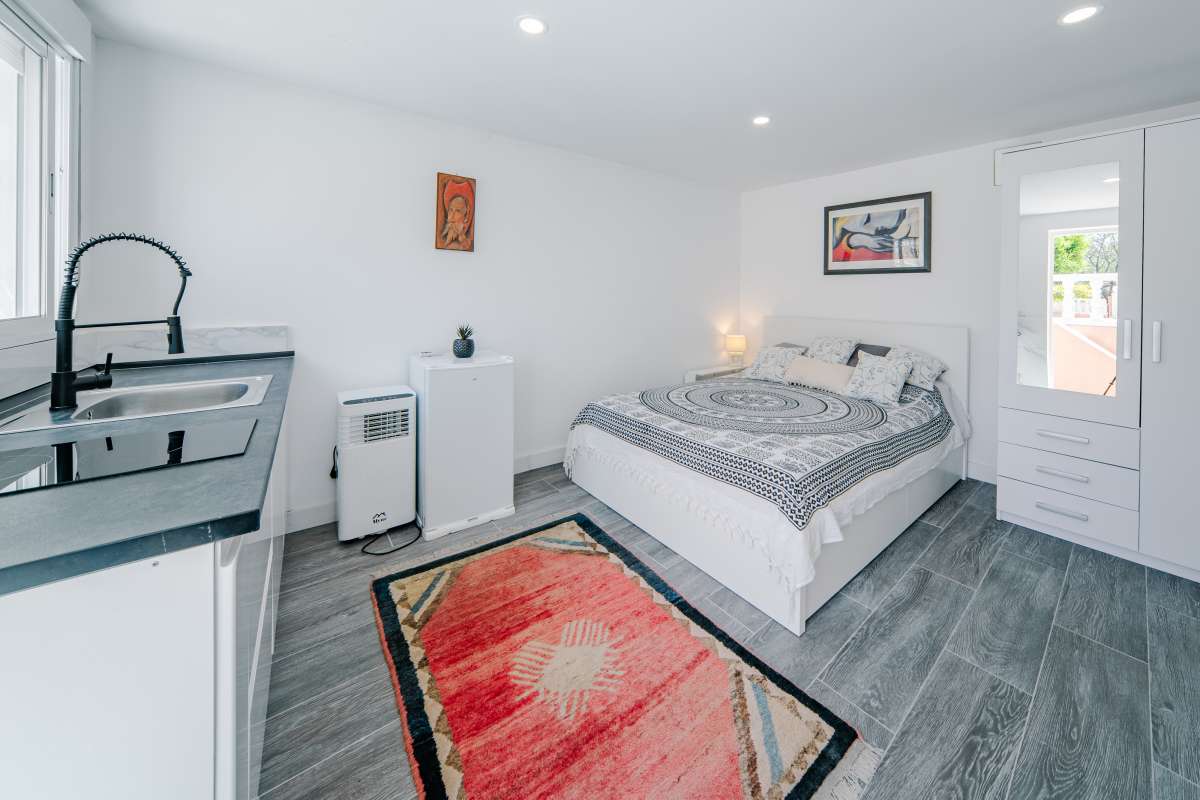 Guest suite with bed, kitchenette and natural light at a renovated Mediterranean villa in La Cometa, Calpe.