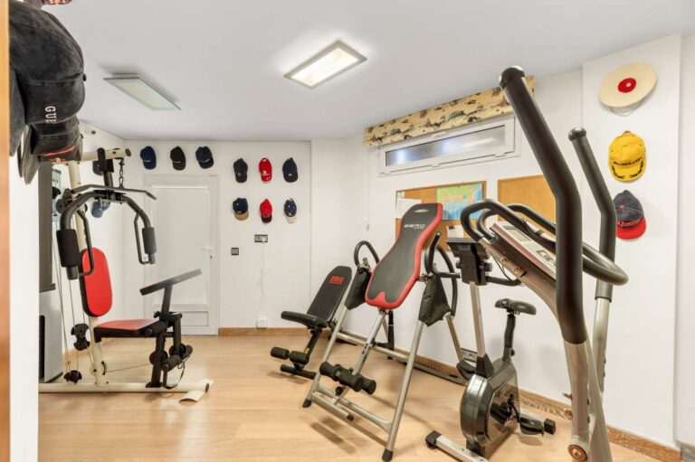 Gym room inside a private villa in Calpe with exercise equipment, storage wall and flexible lower-level space