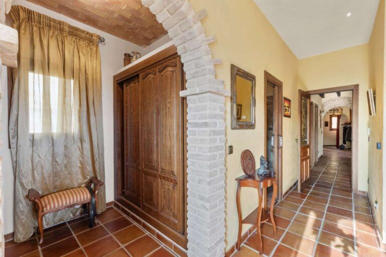Hallway and bedroom area inside a finca-style villa in Benissa Costa with wooden wardrobe, brick arch, terracotta floor and rustic Mediterranean details
