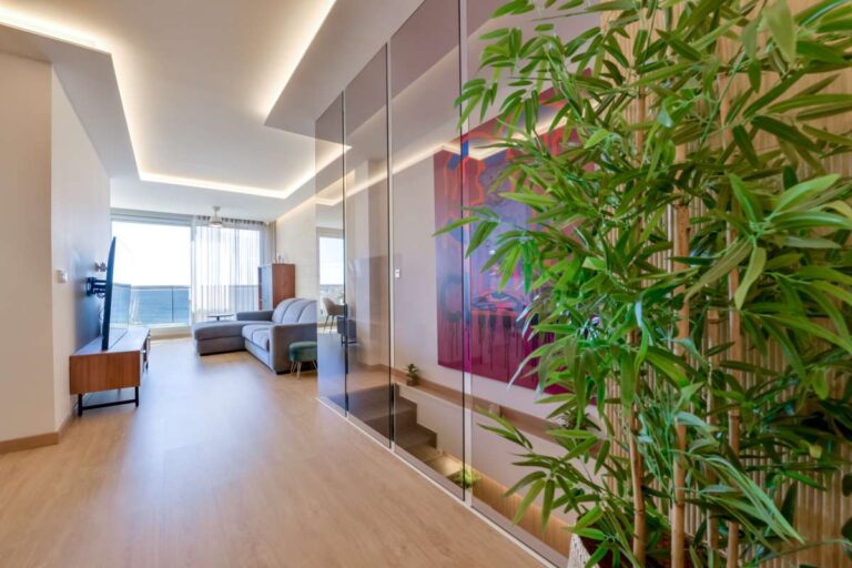 Hallway and lounge area inside a luxury frontline beach duplex in Mascarat, Altea with feature artwork, indoor planting, modern lighting and sea views beyond