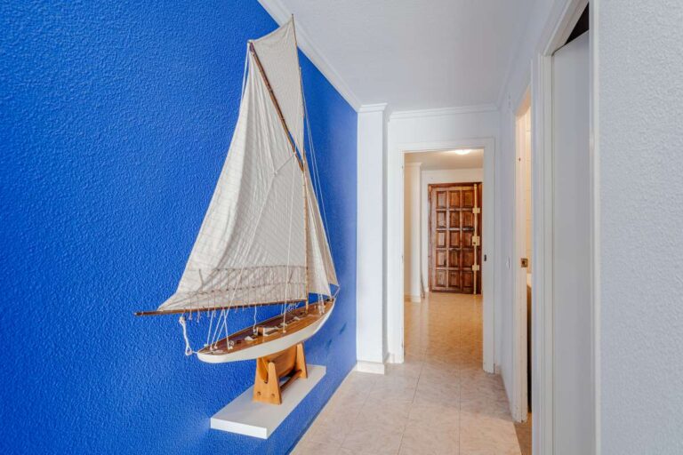Hallway inside a beachfront apartment by La Fossa Beach in Calpe with blue feature wall, nautical decoration and bright corridor layout