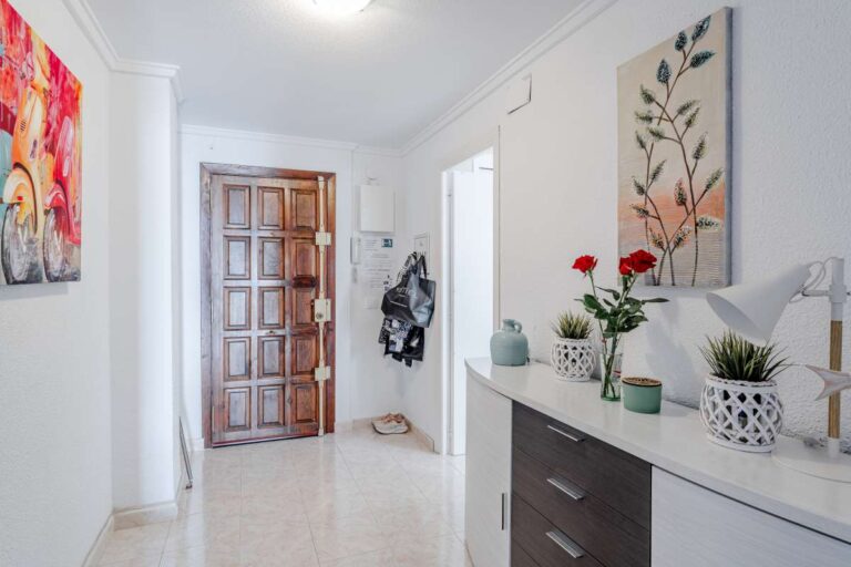 Hallway inside a beachfront apartment by La Fossa Beach in Calpe with decorative artwork, console unit and bright interior finish