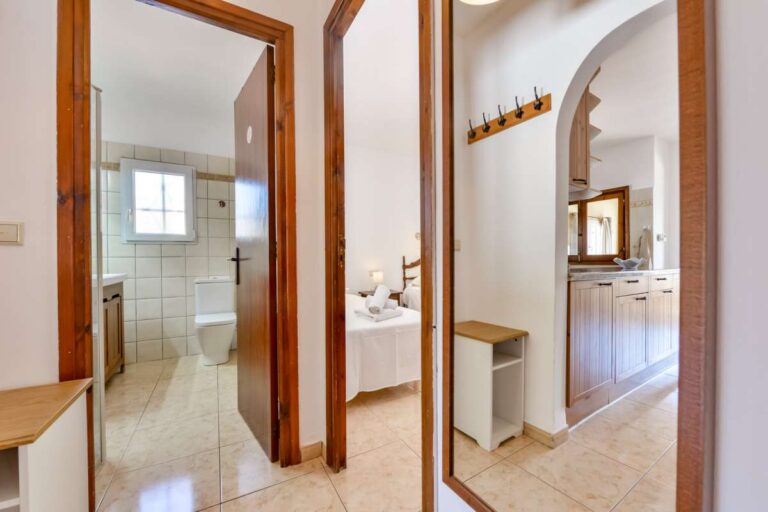 Hallway inside a charming Benissa Coast villa with bathroom access, bedroom access, arched doorway and bright tiled interior