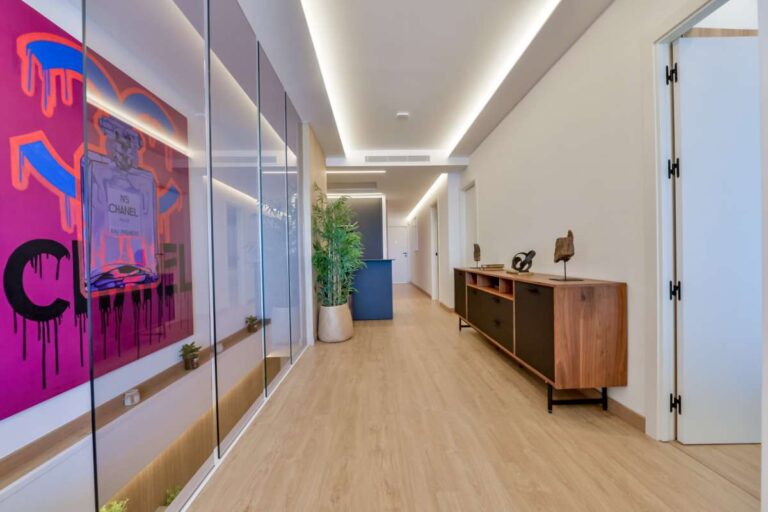 Hallway inside a luxury frontline beach duplex in Mascarat, Altea with modern lighting, feature artwork, console table and wood-effect flooring