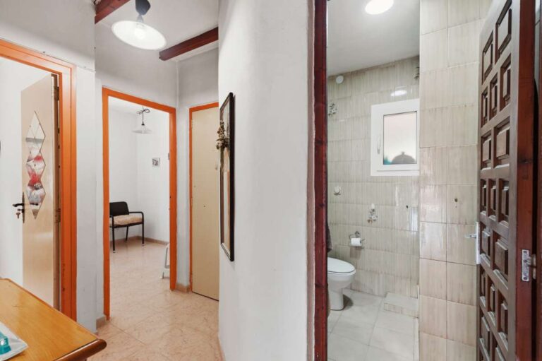 Hallway inside a Mediterranean villa in Benissa Costa with bathroom access, wooden doors and tiled interior finish