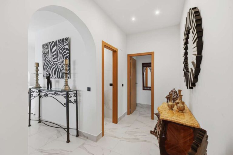 Hallway inside a premium coastal villa on the Benissa Costa with decorative wall mirror, bright white interior and access to bedrooms