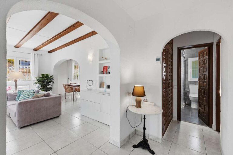 Hallway inside a renovated single-level villa in Moraira with arched openings, beamed ceiling, living room access and bright interior finish