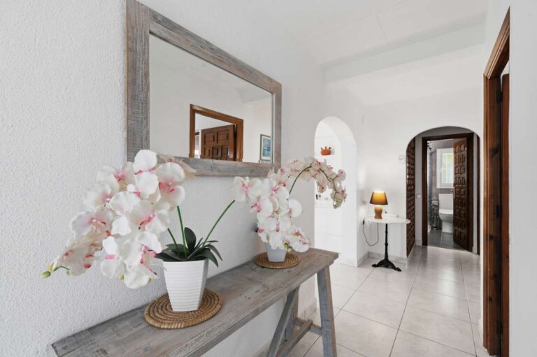 Hallway inside a renovated single-level villa in Moraira with decorative console table, mirror, arched doorway and bright interior finish
