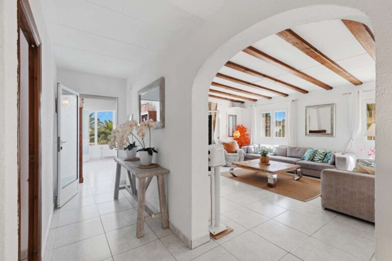 Hallway inside a renovated villa in Moraira leading to the living room with arched opening, beamed ceiling and bright Mediterranean interior