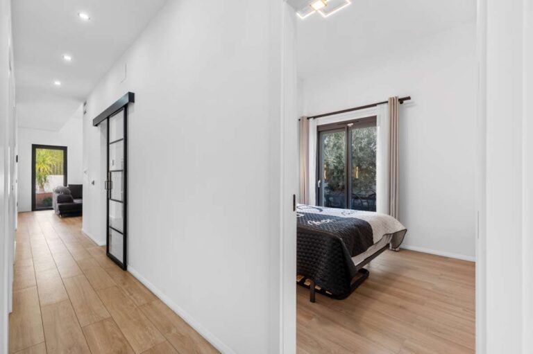 Hallway inside a single-level modern villa in Santa Clara, Altea with bedroom access, wood flooring, white walls and modern sliding door