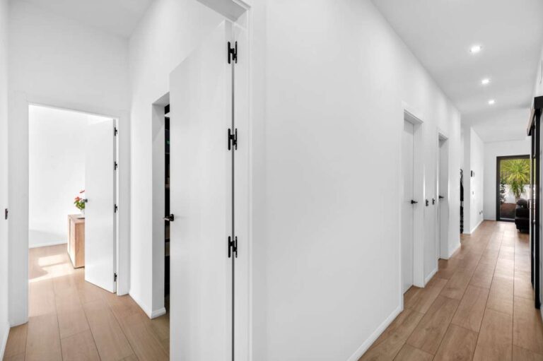 Hallway inside a single-level modern villa in Santa Clara, Altea with wood flooring, white walls, recessed lighting and bedroom access