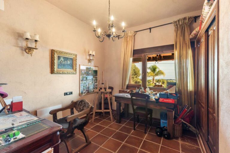 Home office inside a finca-style villa in Benissa Costa with terracotta tiled floor, chandelier lighting, large window and sea views