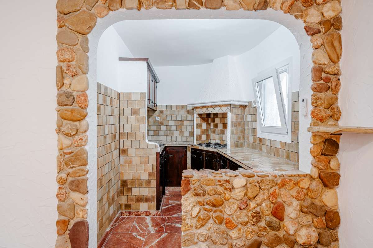 Interior archway with stone detailing and tiled kitchen area inside a Mediterranean villa in Maryvilla, Calpe.