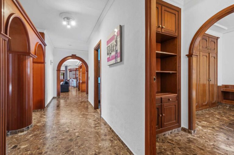 Interior hallway with arched wooden doors and tiled flooring inside a spacious villa with guest apartments in Calpe.