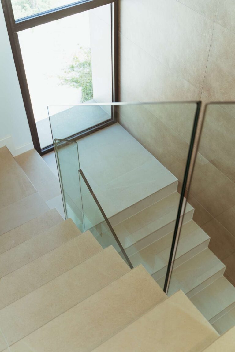 Interior staircase inside a new-build luxury villa in Moraira with glass balustrade, large window and bright contemporary finish